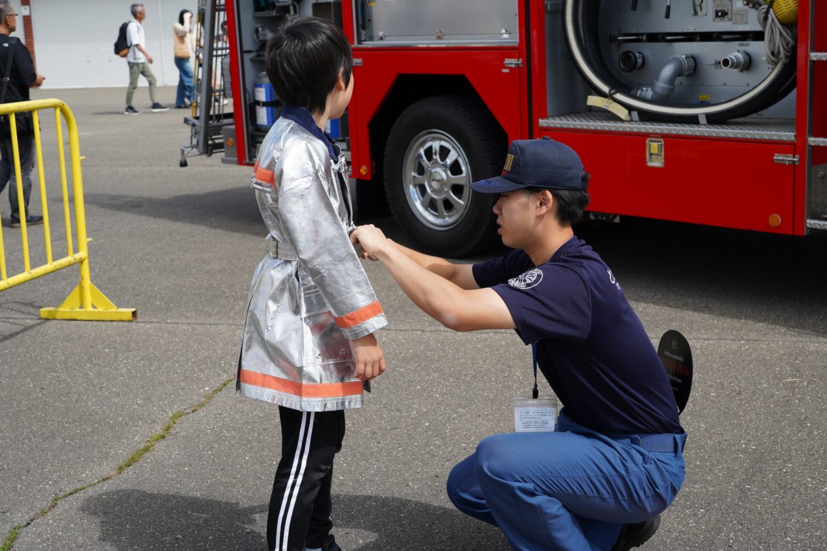 子供用の防火服を着させる消防隊員